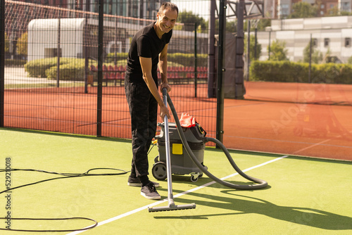 man with professional vacuum cleaner for the tennis court © Angelov