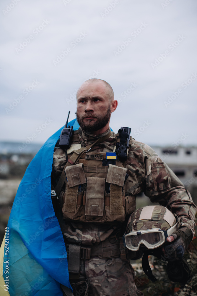 A military man holds the flag of Ukraine. Portrait of the defender of Ukraine. A military man holds the flag of Ukraine. Portrait of the defender of Ukraine.