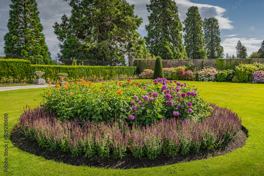 Circular flowerbed in beautiful Powerscourt garden with hedges, decorative trees, fountains and forest, Enniskerry, Wicklow, Ireland