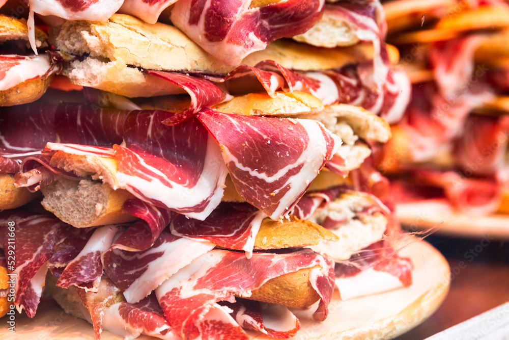 traditional Spanish bocadillos with Iberico jamon laid out in a slide on a shop window traditional Spanish bocadillos with Iberico jamon laid out in a slide on a shop window
