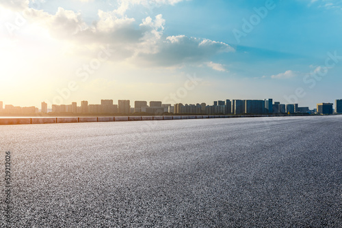 Asphalt road and modern city skyline with buildings scenery at sunset