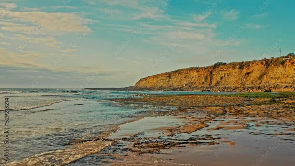 Drone is flying along beautiful ocean shore shallow water. Drone flies low over the surface of the water along the rocky shore during sunset. Beautiful natural landscape with ocean rocky shore. Drone is flying along beautiful ocean shore shallow water. Drone flies low over the surface of the water along the rocky shore during sunset. Beautiful natural landscape with ocean rocky shore.