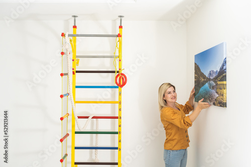 Woman hanging a photo canvas on a wall.