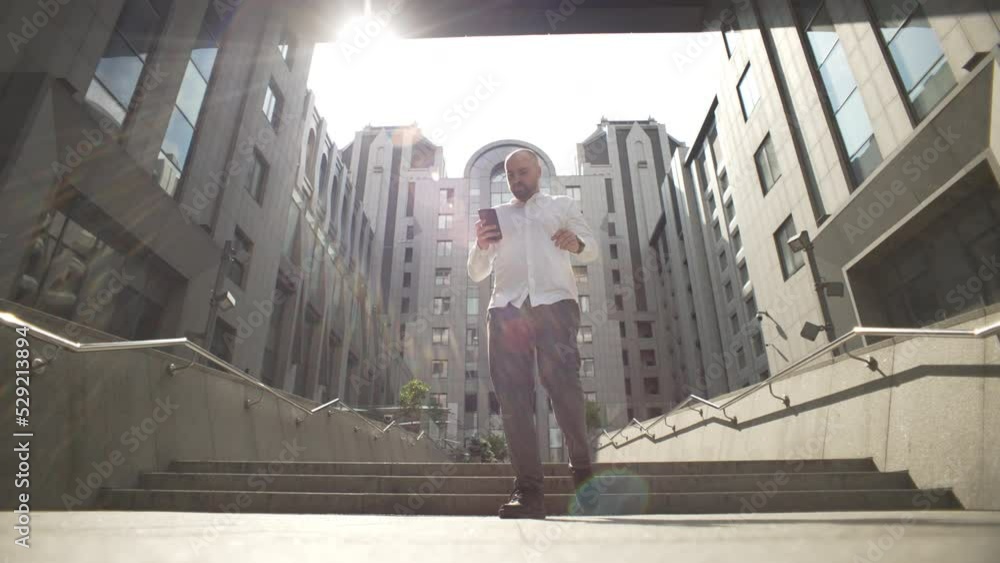 The manager goes and chats on the phone near the business center. A man solves work matters by typing on a smartphone. High quality 4k footage The manager goes and chats on the phone near the business center. A man solves work matters by typing on a smartphone. High quality 4k footage