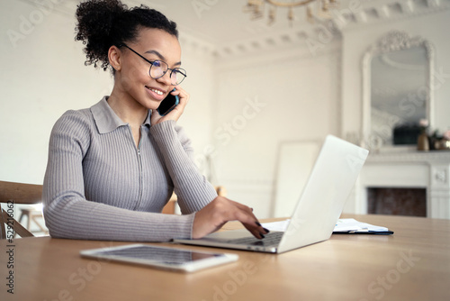 Female freelancer uses laptop on desk chat online video call working in new office