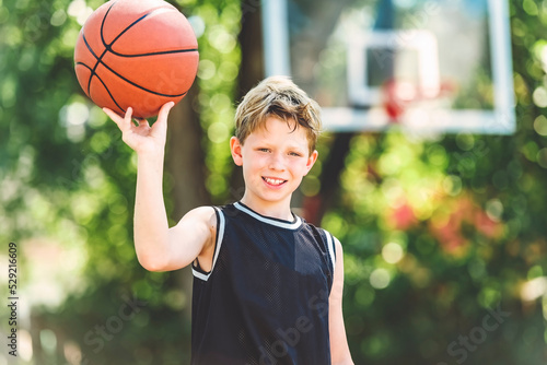 portrait of a boy kid playing with a basketball in park © Louis-Photo