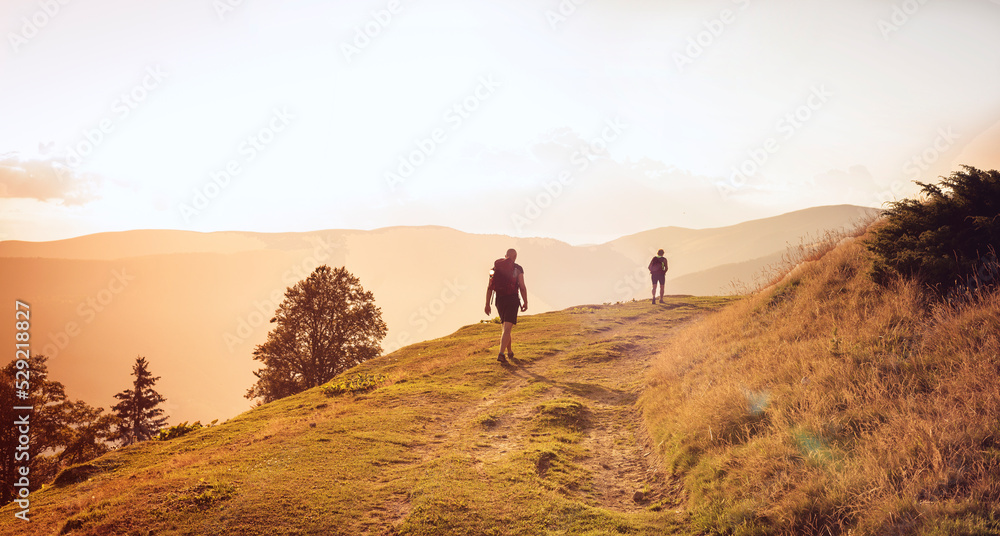 People on a hike in the mountains go along the route in the Carpathians during sunset.