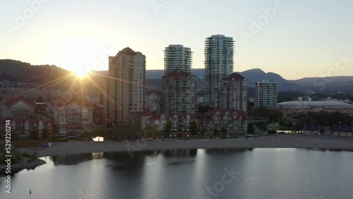 Aerial of sun rising over mountains behind Downtown Kelowna city skyline