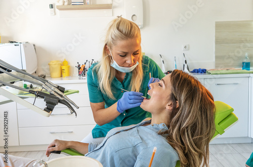 Female dentist examining a patient s teeth in the dentist office.  