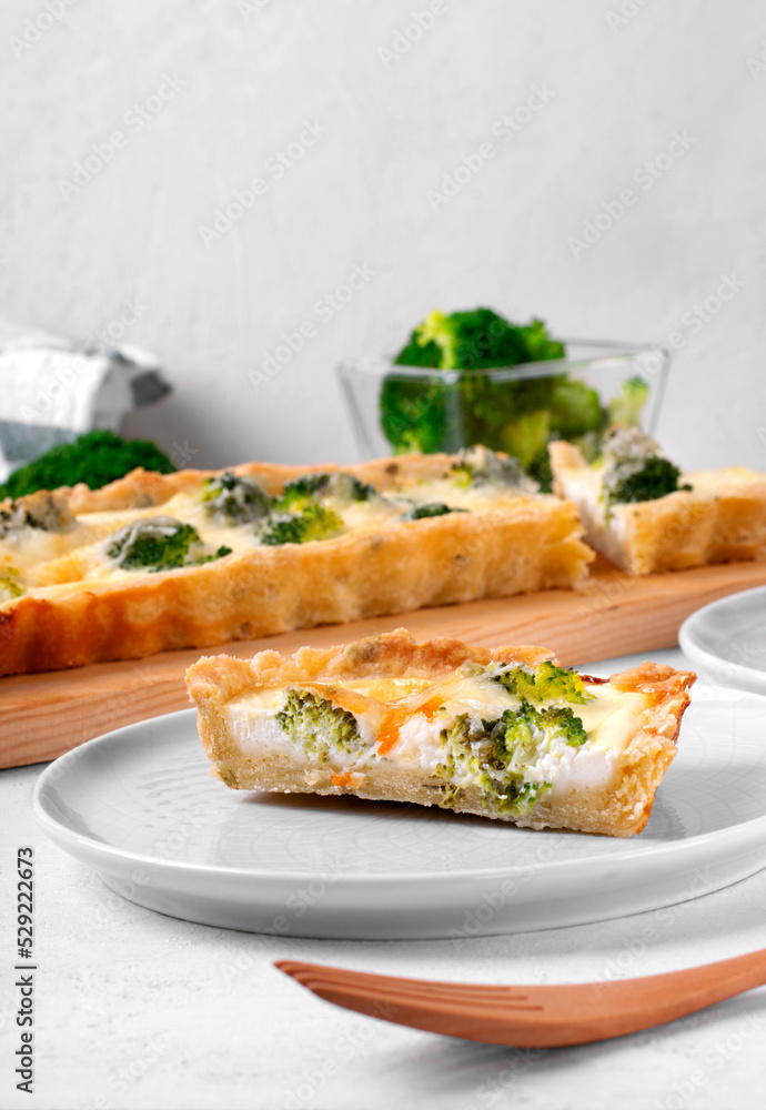 Piece of broccoli tart on shortbread dough on the white table. Savory pie Piece of broccoli tart on shortbread dough on the white table. Savory pie
