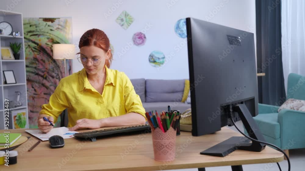 designer, creative female in glasses draws a print on paper using felt-tip pens for shoes sitting at table in room designer, creative female in glasses draws a print on paper using felt-tip pens for shoes sitting at table in room