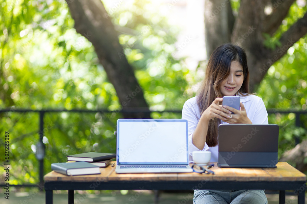 Outdoor business woman wearing casual clothes is working on a laptop and modern equipment in a natural and comfortable setting. Outdoor business woman wearing casual clothes is working on a laptop and modern equipment in a natural and comfortable setting.