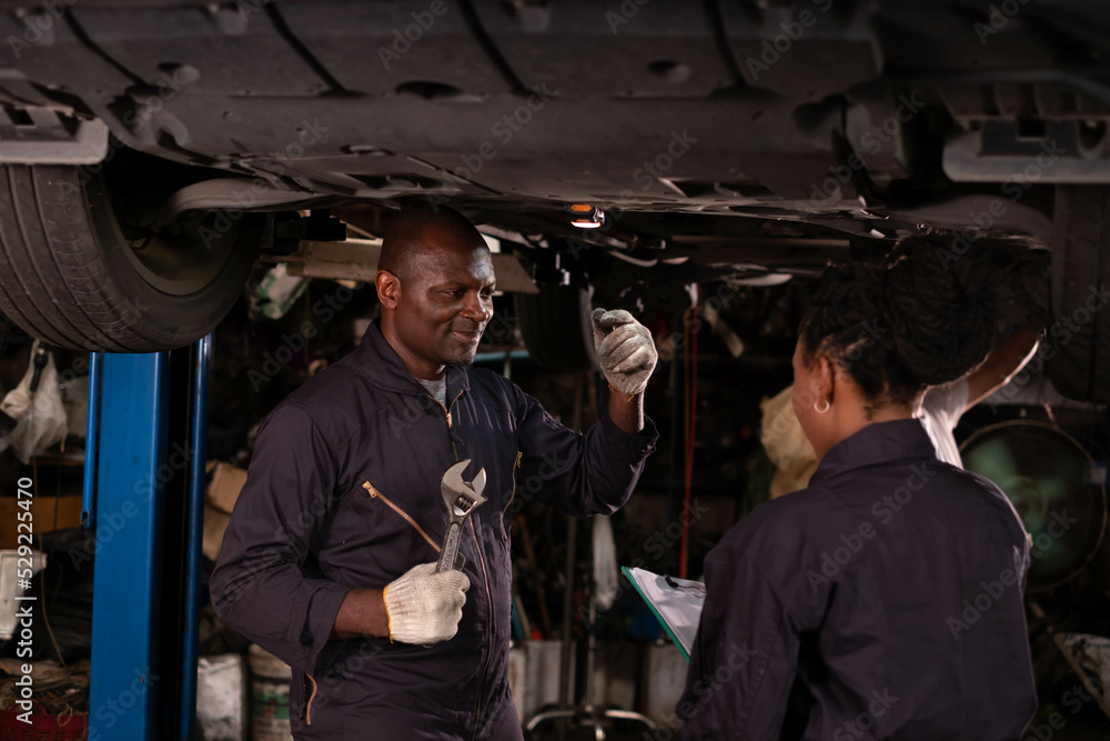 African american Two mechanics - man examining car engine. Auto mechanic working in garage.Car Mechanic Detailed Vehicle Inspection. Auto Service Center Theme. African american Two mechanics - man examining car engine. Auto mechanic working in garage.Car Mechanic Detailed Vehicle Inspection. Auto Service Center Theme.