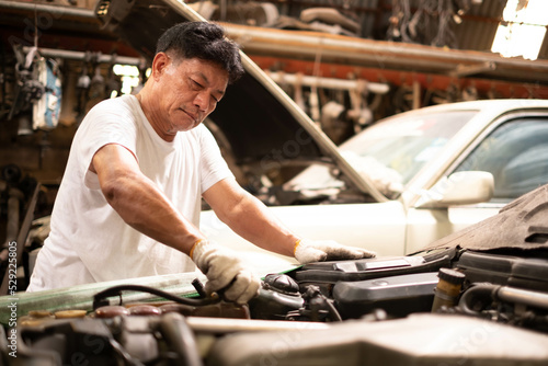 male mechanic repairs car in garage. Car maintenance and auto service garage concept. Auto mechanic working in garage.Car Mechanic Detailed Vehicle Inspection. © Montri