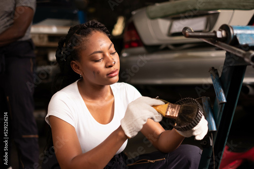 African american technician female Mechanic working under the hood at the repair garage.