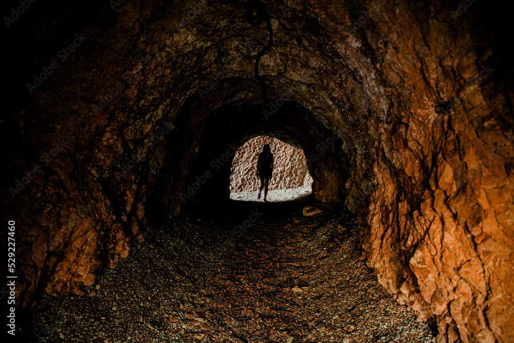 Obraz premium Journey. The woman walks along the cliff into the cave.