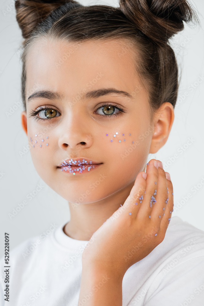 portrait of cute girl with sparkling glitter stars on lips and cheeks looking at camera isolated on white. portrait of cute girl with sparkling glitter stars on lips and cheeks looking at camera isolated on white.