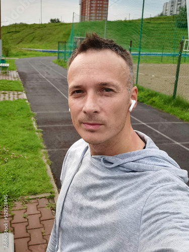 selfie portrait of a sporty man in headphones at the city stadium