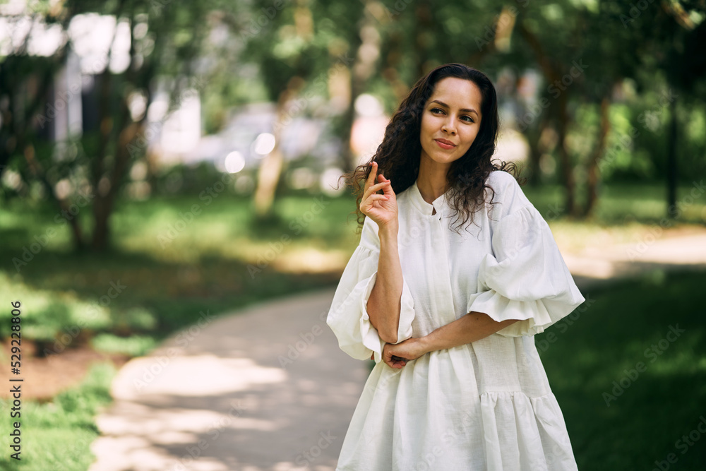 Curly-haired brunette girl in the park. Girl thinking and holding her hair. High quality photo Curly-haired brunette girl in the park. Girl thinking and holding her hair. High quality photo