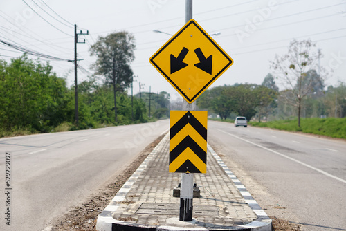 Yellow warning road sign with symbol of arrows on the road for the two way run in rural of Thailand. 