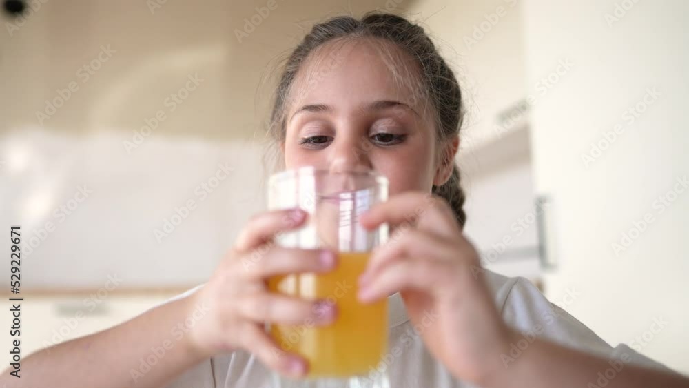 girl child drinking juice. happy family a healthy eating kid dream concept. daughter girl drinking yellow juice from a indoors glass cup in the kitchen. child drinking fruit juice girl child drinking juice. happy family a healthy eating kid dream concept. daughter girl drinking yellow juice from a indoors glass cup in the kitchen. child drinking fruit juice