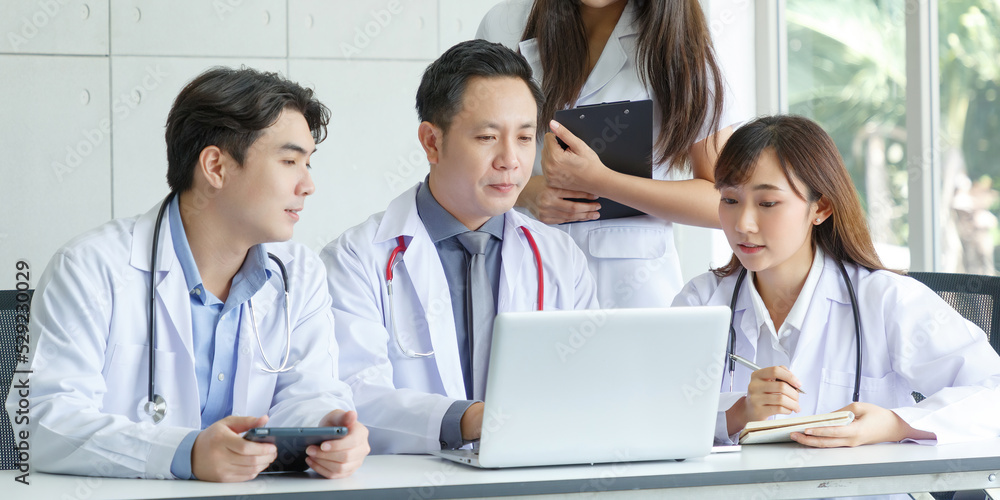 Young asian intern, young male and female doctor sitting with Senior Doctor talk and discuss using laptop in office. Young asian intern, young male and female doctor sitting with Senior Doctor talk and discuss using laptop in office.