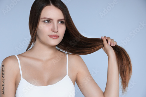 Young woman with strong healthy hair on light blue background