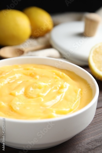 Delicious lemon curd in bowl on dark wooden table, closeup