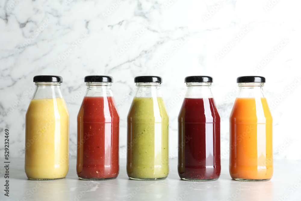 Bottles with delicious colorful juices on marble table Bottles with delicious colorful juices on marble table