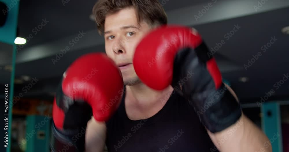 Boxer training in a gym. Sportsman boxing in camera. Muay thai fighter punching. Boxer training in a gym. Sportsman boxing in camera. Muay thai fighter punching.