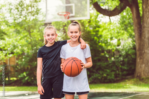 two girl child in sportswear playing basketball game