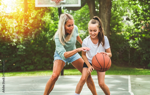 Mother and little daughter play basketball outside © Louis-Photo
