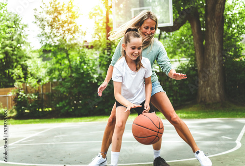 Mother and little daughter play basketball outside © Louis-Photo