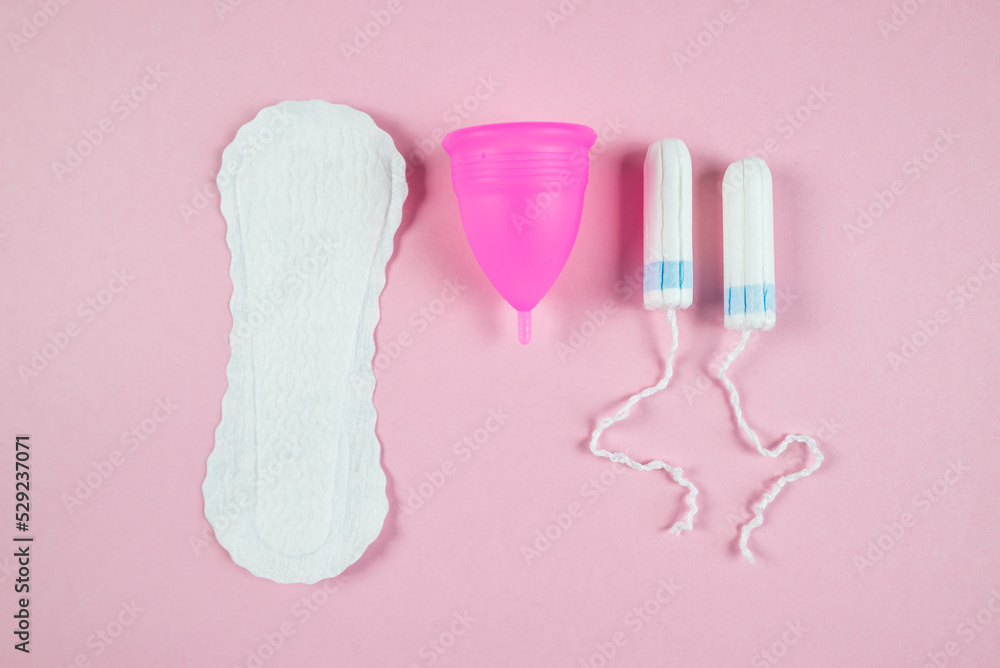 women's tampons, menstrual cup, pads on a pink background. Feminine hygiene. Menstruation.