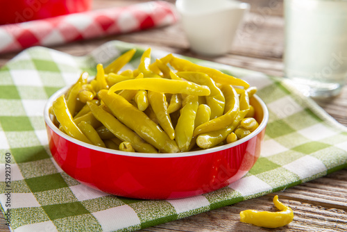 Pickled spicy green pepper in red bowl