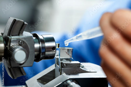 Closeup a scientist adding water to glass knife with waterboat mounted on an ultramicrotome to make sections for the electron microscope photo