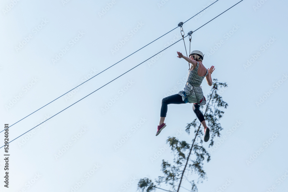 A young girl descends from a height on cables on a cable car.