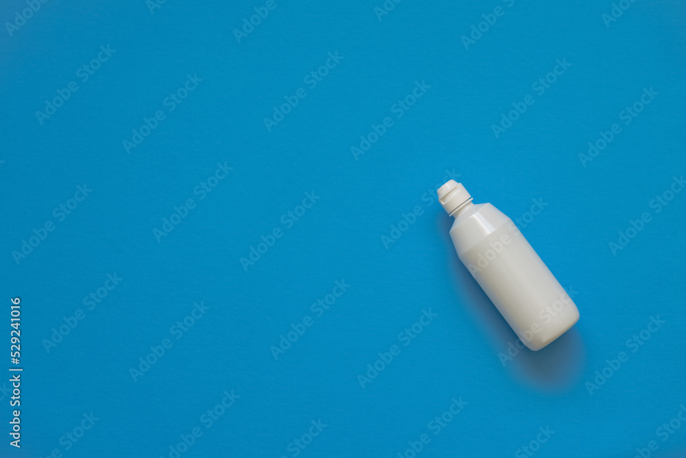 On a blue background, a bottle with a solution. Lens solution. Soft focus On a blue background, a bottle with a solution. Lens solution. Soft focus