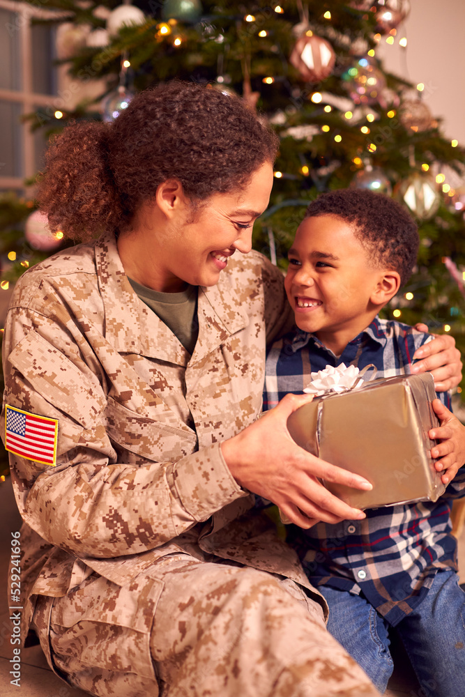 American Female Soldier In Uniform Home On Leave For Christmas Giving Son Present