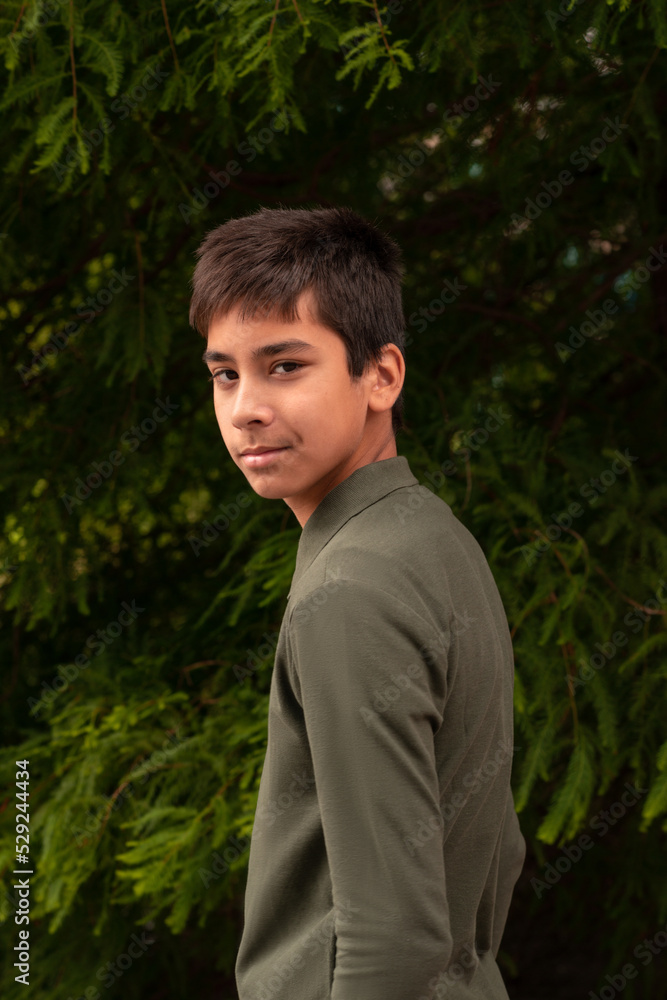 A young smiling guy standing against agreen tree A young smiling guy standing against agreen tree