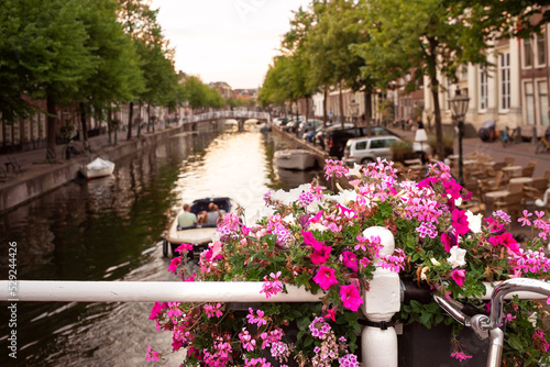 Flowers on the bridge over the river flowing in the city with historical architecture.