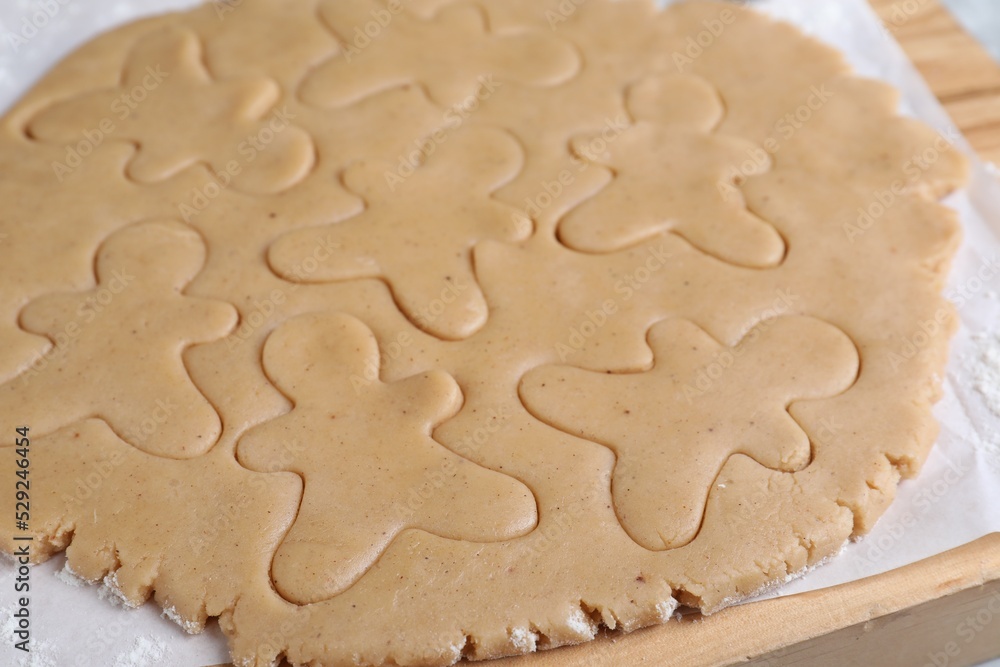 Making homemade Christmas cookies. Dough for gingerbread men on wooden board, closeup Making homemade Christmas cookies. Dough for gingerbread men on wooden board, closeup