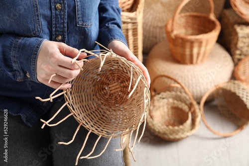 Fotografie Woman weaving wicker basket indoors, closeup view