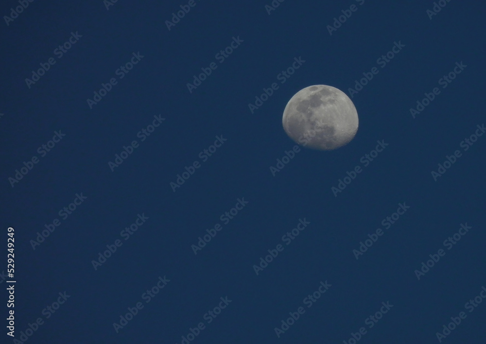 Luna plateada en cuarto menguante sobre un cielo azul, celeste, sin nubes 