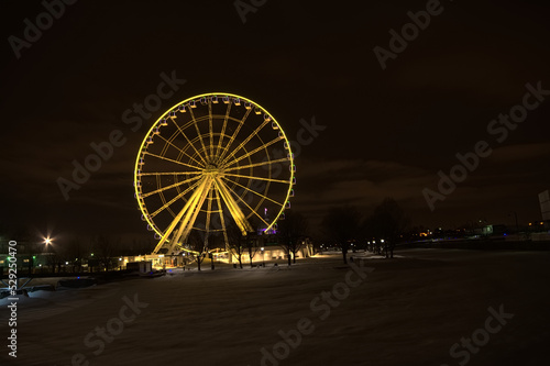Illuminated ferris wheel at night on a cold winter day with snow on the ground in the Old Port of Montreal, Quebec, Canada. Long exposure with motion blur