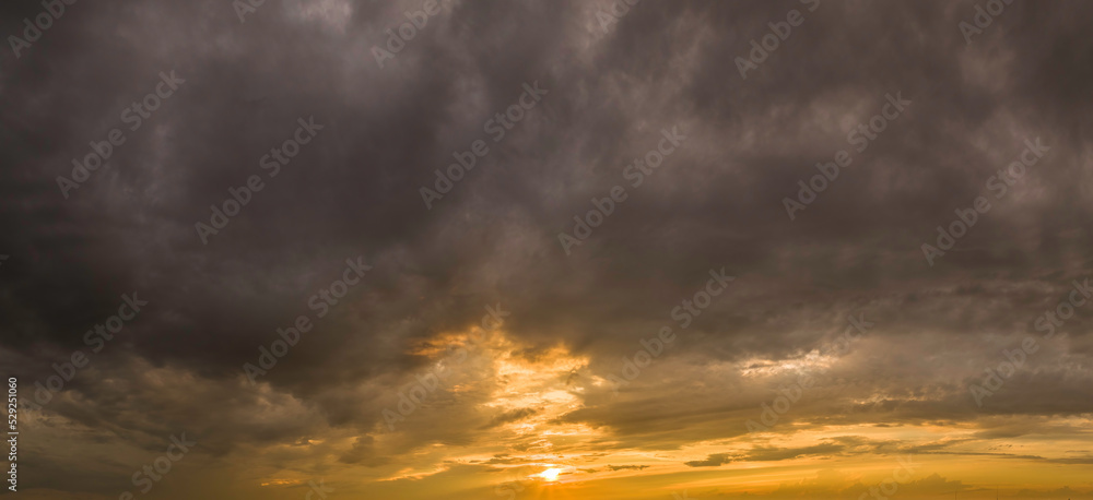 Thunder clouds with yellow sunset background