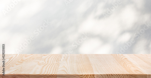 Selective focus.White wood table top with shadow of tree leaf on wall background