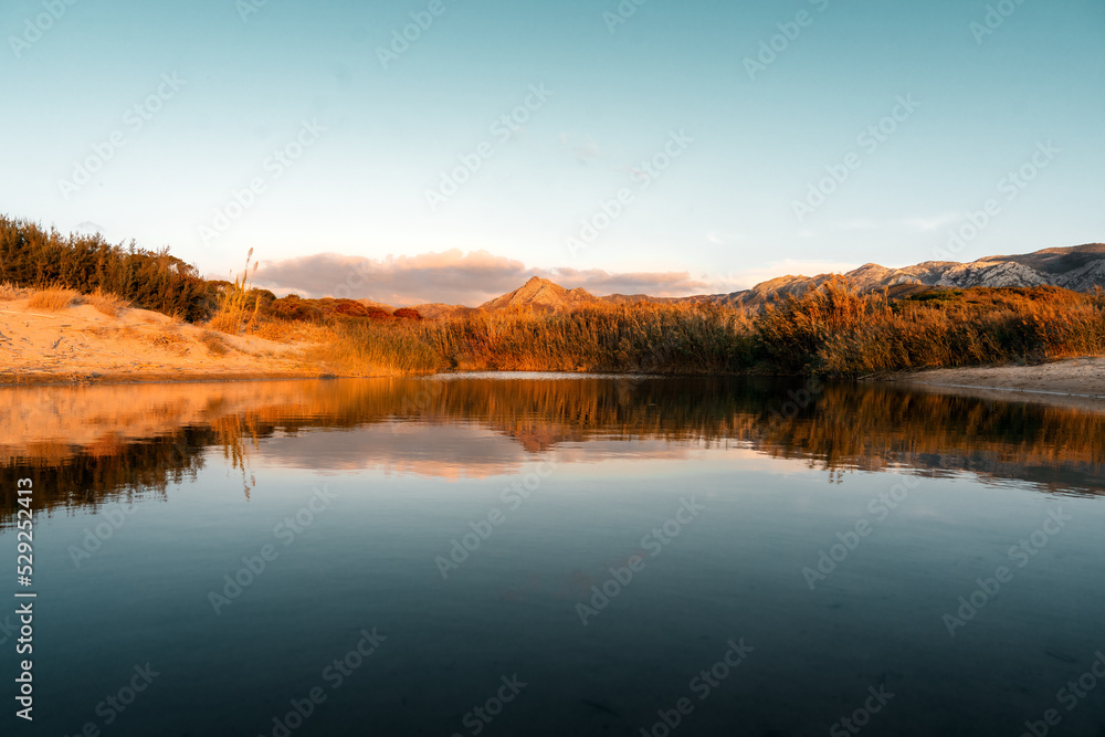 Blick ins Land und die Berge bei Sonnenuntergang am Sandstrand Spiaggia di Portixeddu auf Sardinien Italien im Mittelmeer