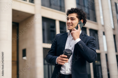 A manager in a business suit is talking on the phone and goes to the office. Businessman man career in a new job.