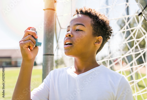 Child is using an asthma inhaler in park photo
